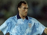 A soccer player wearing a light blue England jersey, looking focused during a match.