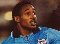 A goalkeeper in a light blue jersey looking to the side with a concerned expression, likely during a football match.